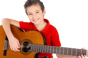 Handsome happy  boy is playing on acoustic guitar - isolated on white background